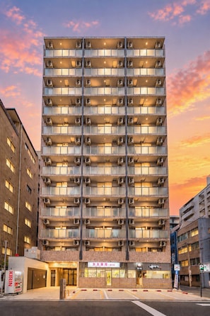 Ett hotell med flera våningar, en enhetlig fasad, luftkonditioneringsanläggningar och en entré i markplan med skyltar.