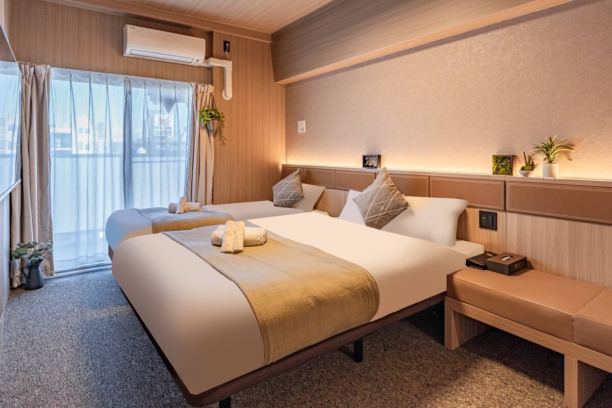 Une chambre d’hôtel moderne avec un grand lit, des tables de chevet, un bureau et une vue par la fenêtre.
