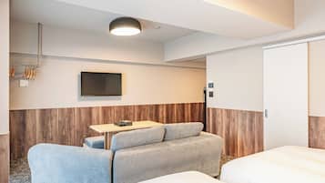 A hotel room with a sofa, a small table, a TV, and a wardrobe.