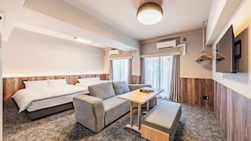 A hotel room with a bed, sofa, table, and TV.