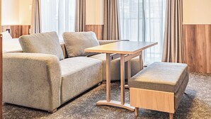 Ett modernt hotellrum med en soffa, ett litet bord och en bänk.