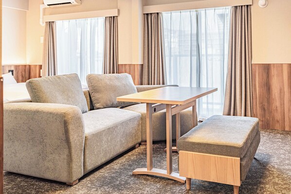 A modern hotel room with a sofa, a small table, and a bench. - Apartment Hotel 11 Dotonbori II (Osaka)