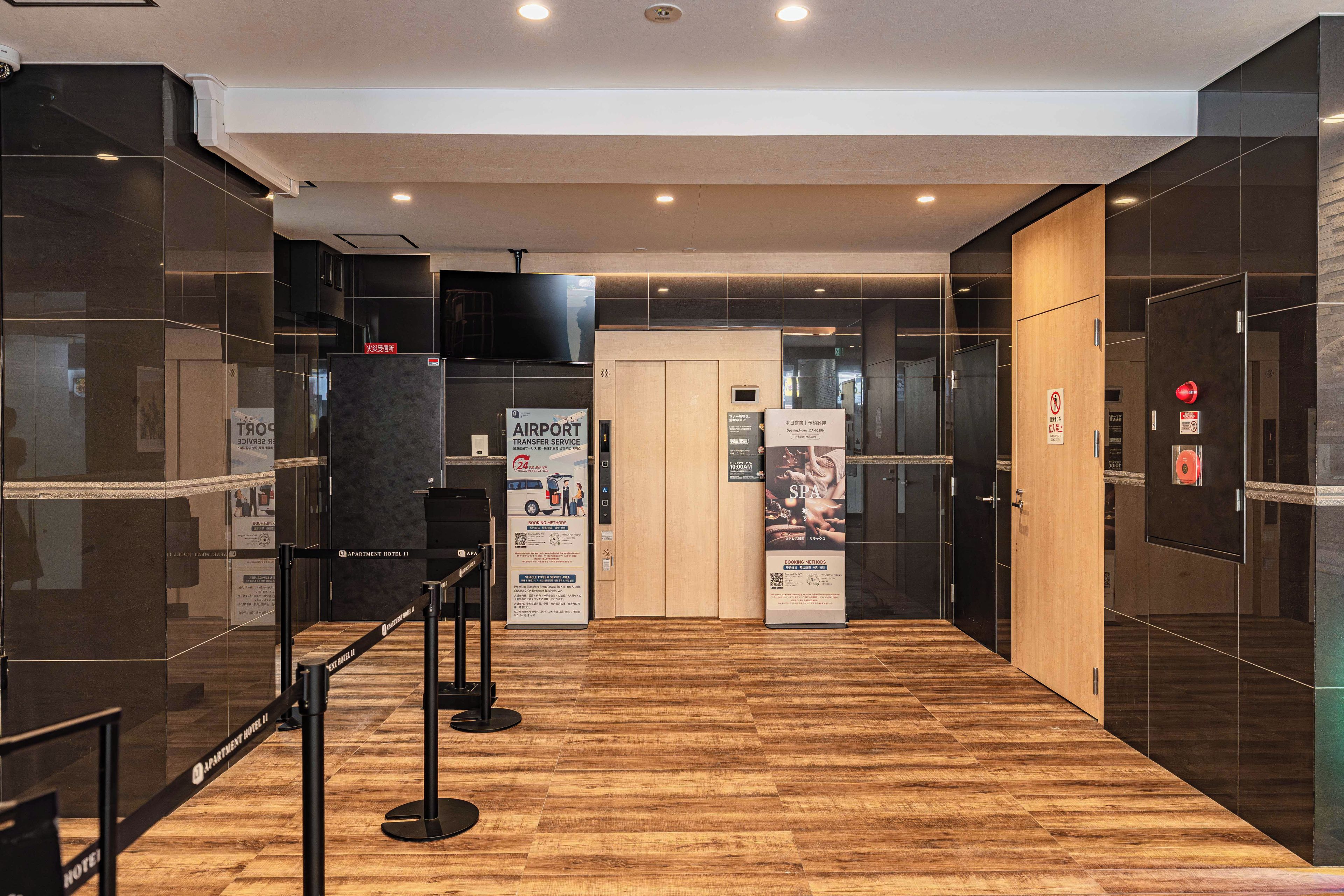 A modern hotel lobby with a check-in counter, a wooden floor, and glass walls.