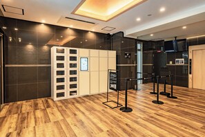 A hotel lobby with a wooden floor, a reception desk, a white storage unit, and a black elevator. - Apartment Hotel 11 Dotonbori II (Osaka)