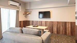 Ett modernt hotellrum med en soffa, ett litet bord, en platt-TV och en luftkonditioneringsanläggning.