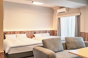Een hotelkamer met twee bedden, een bank, een tafel en een raam met gordijnen.