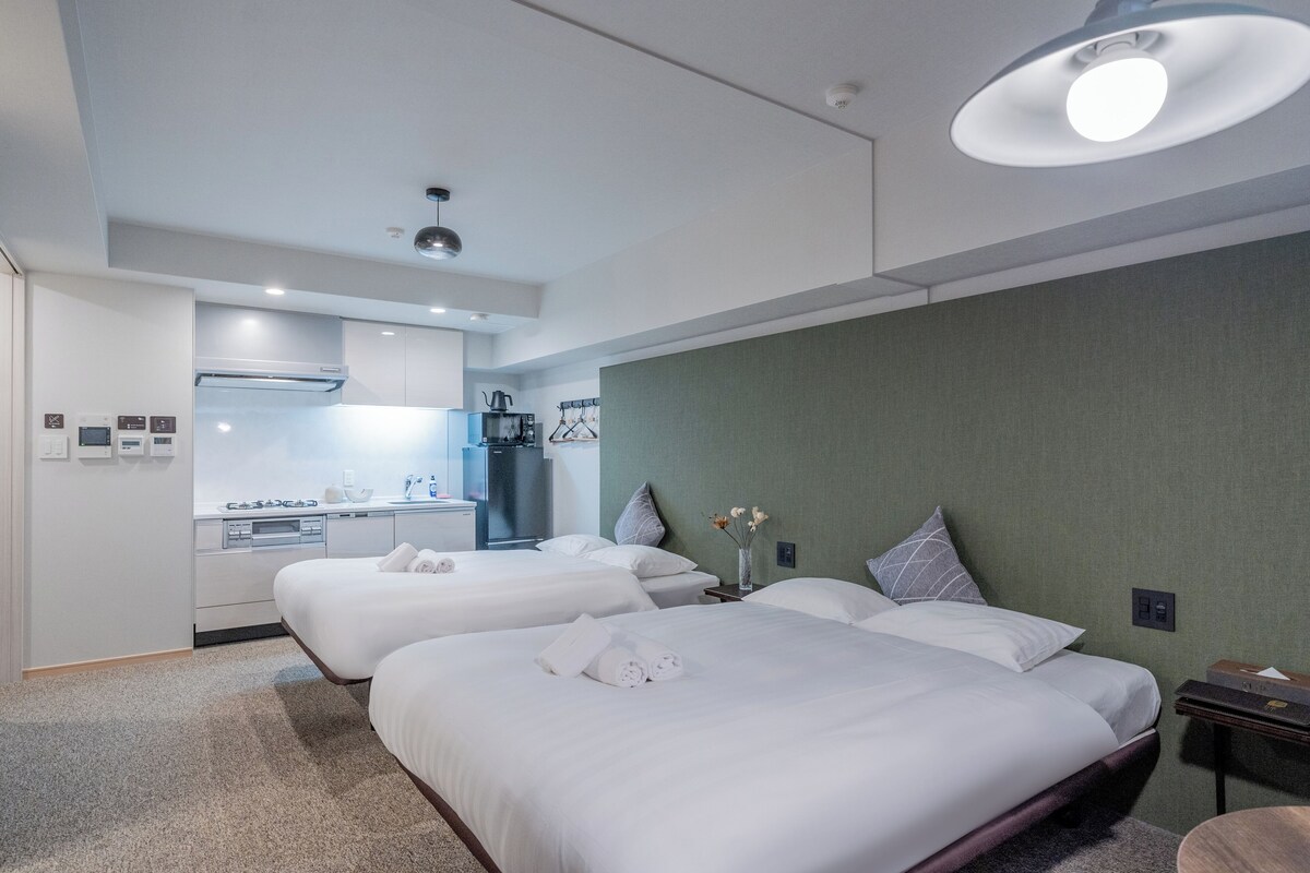 Ein Hotelzimmer mit zwei Betten, einer Küchenzeile und einem Badezimmer.