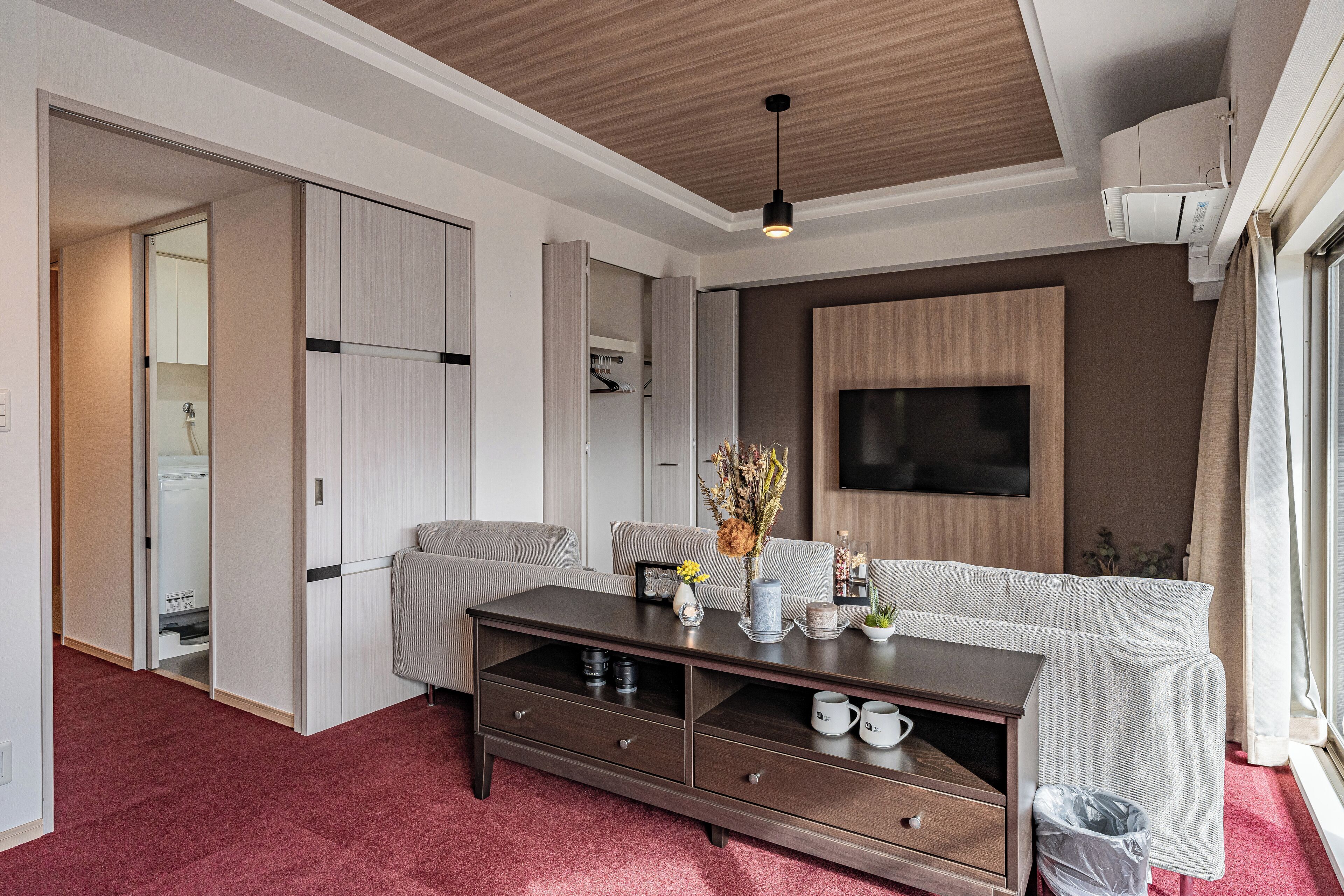 A modern living room with a sofa, TV, and a wooden cabinet.