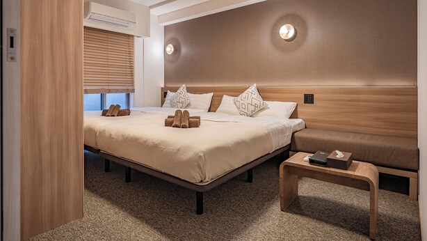 A modern hotel room with a large bed, a bedside table, and a built-in bench. - Apartment Hotel 11 Shinsaibashi (Osaka)