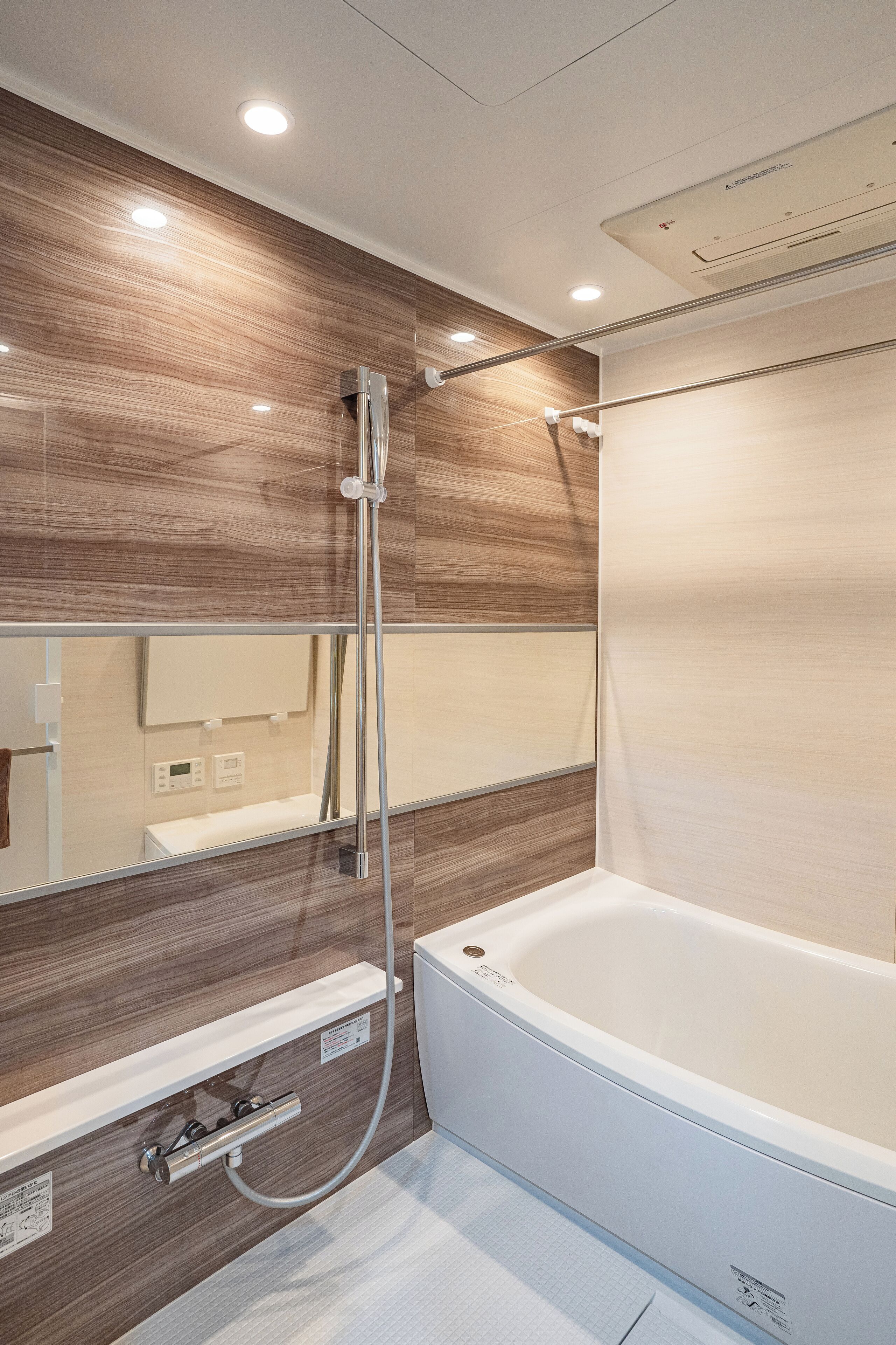 A modern bathroom with a wooden wall panel, a large mirror, a bathtub, and a shower area.