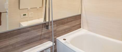 A modern bathroom with a wooden wall panel, a large mirror, a bathtub, and a shower area.