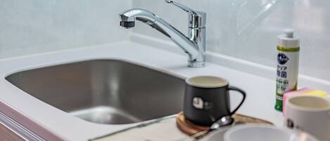 A modern kitchen sink with a chrome faucet, a coffee maker, and a bottle of dish soap on the counter.