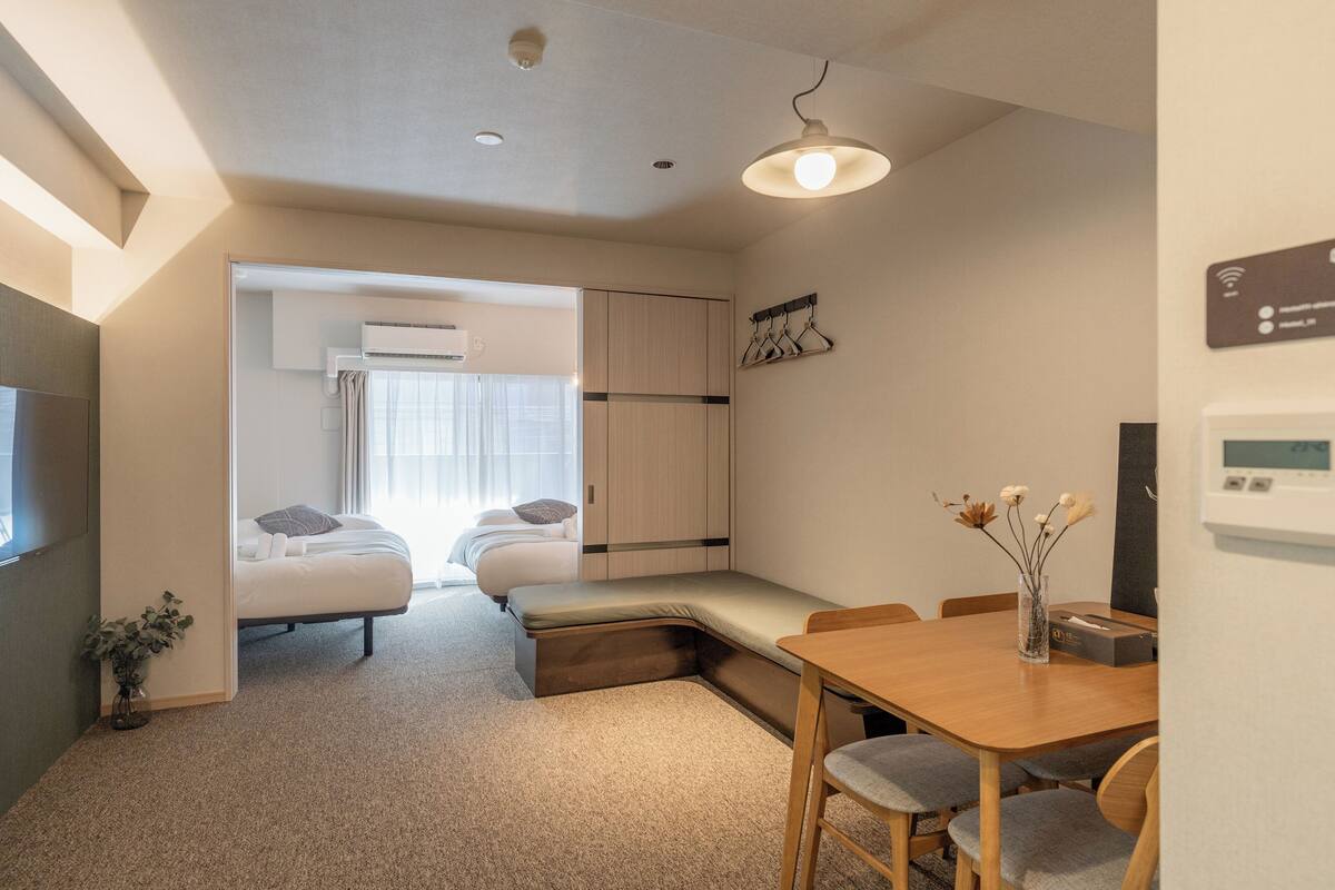 A compact hotel room with a bed, a small dining table, and a seating area.