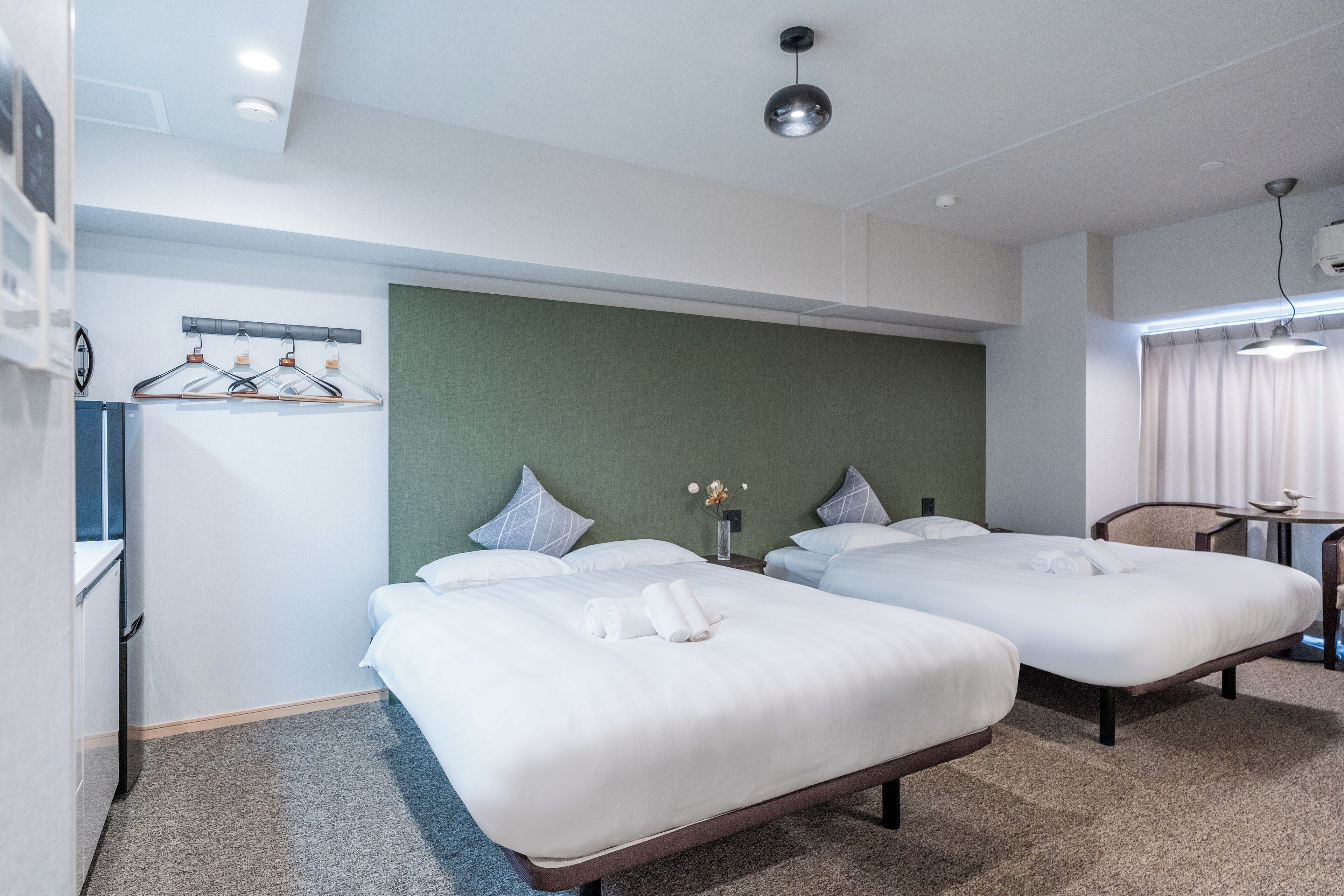 Une chambre d’hôtel avec deux lits simples, un bureau et une chaise.