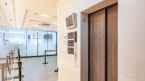 A modern elevator with a digital display, a wooden door, and informational signs on the wall. - Apartment Hotel 11 Shinsaibashi (Osaka)