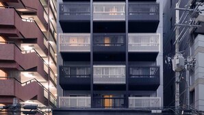 Een meerhoog gebouw met een modern ontwerp, met balkons en een gelijkvloerse ingang met glazen deuren.
