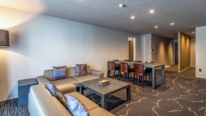 Een moderne hotelkamer met een bank, een salontafel, en een zithoek met stoelen en een tafel.