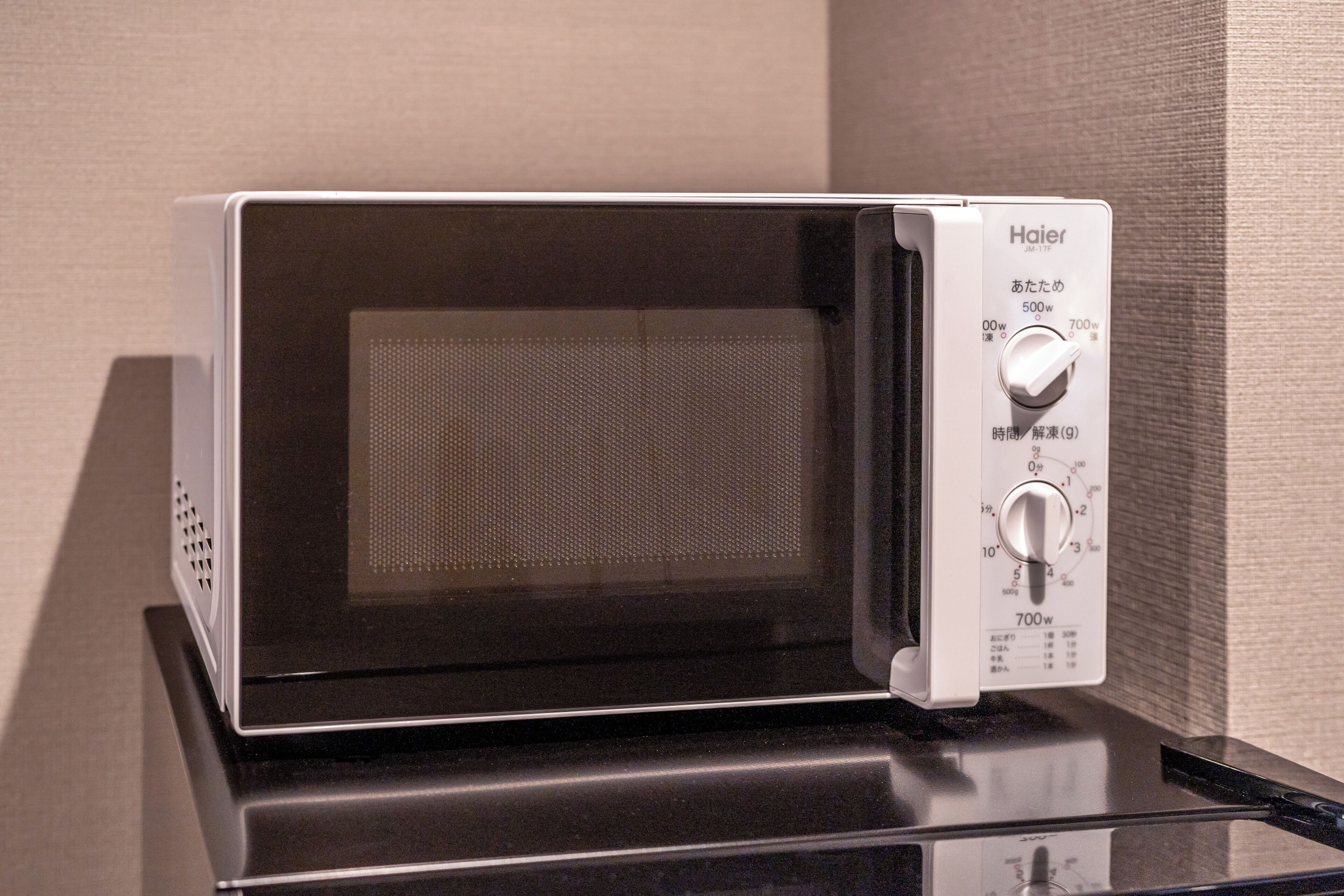 A Haier microwave oven with a digital display and control panel on a black countertop.