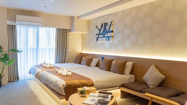 Een hotelkamer met een groot bed, een bank, een kleine tafel en een potplant.