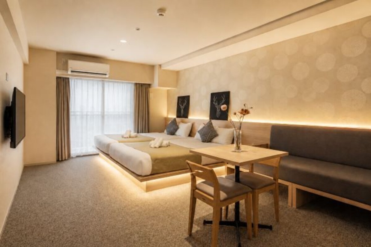 Una camera d'albergo con un letto, un divano, un tavolo da pranzo e una TV.