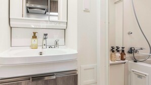 Un baño moderno con un espejo grande, un lavamanos y una zona de ducha.