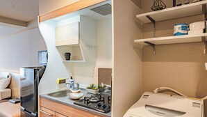 A compact kitchen with a refrigerator, stove, sink, and a microwave. There are cabinets and a countertop. - Apartment Hotel 11 Namba Minami III (Osaka)