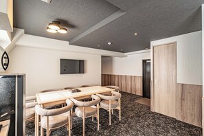 Un intérieur moderne avec une table et des chaises en bois, un téléviseur à écran plat et une porte dotée d’un panneau en bois.