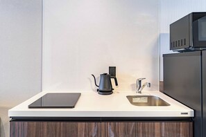 A modern kitchen with a black kettle, a sink, and a microwave above it. - Apartment Hotel 11 Shinsaibashi 4 (Osaka)