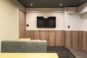 Ein moderner Kinoraum mit einem an der Wand befestigten Flachbildfernseher, Holzverkleidung und Teppichboden.