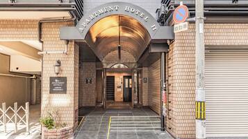 The entrance to a hotel with a covered entrance, a sign indicating no parking, and a sign for the 11th apartment.