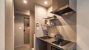 A compact kitchenette with a built-in stove, microwave, and sink. - Apartment Hotel 11 Namba Minami Shin-Imamiya (Osaka)