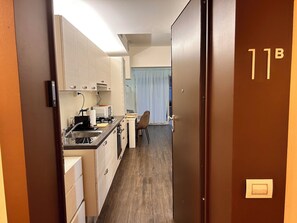 A compact hotel room with a kitchenette, a dining area, and a bathroom. - Luxury and Comfortable Studio With Elegant Patio - Golden Fish Florence - (Firenze)