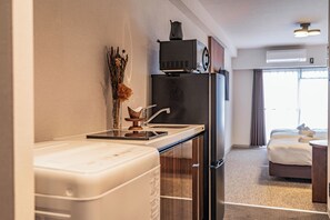 Une chambre d’hôtel moderne équipée d’une kitchenette, d’un lit et offrant une vue sur l’extérieur.