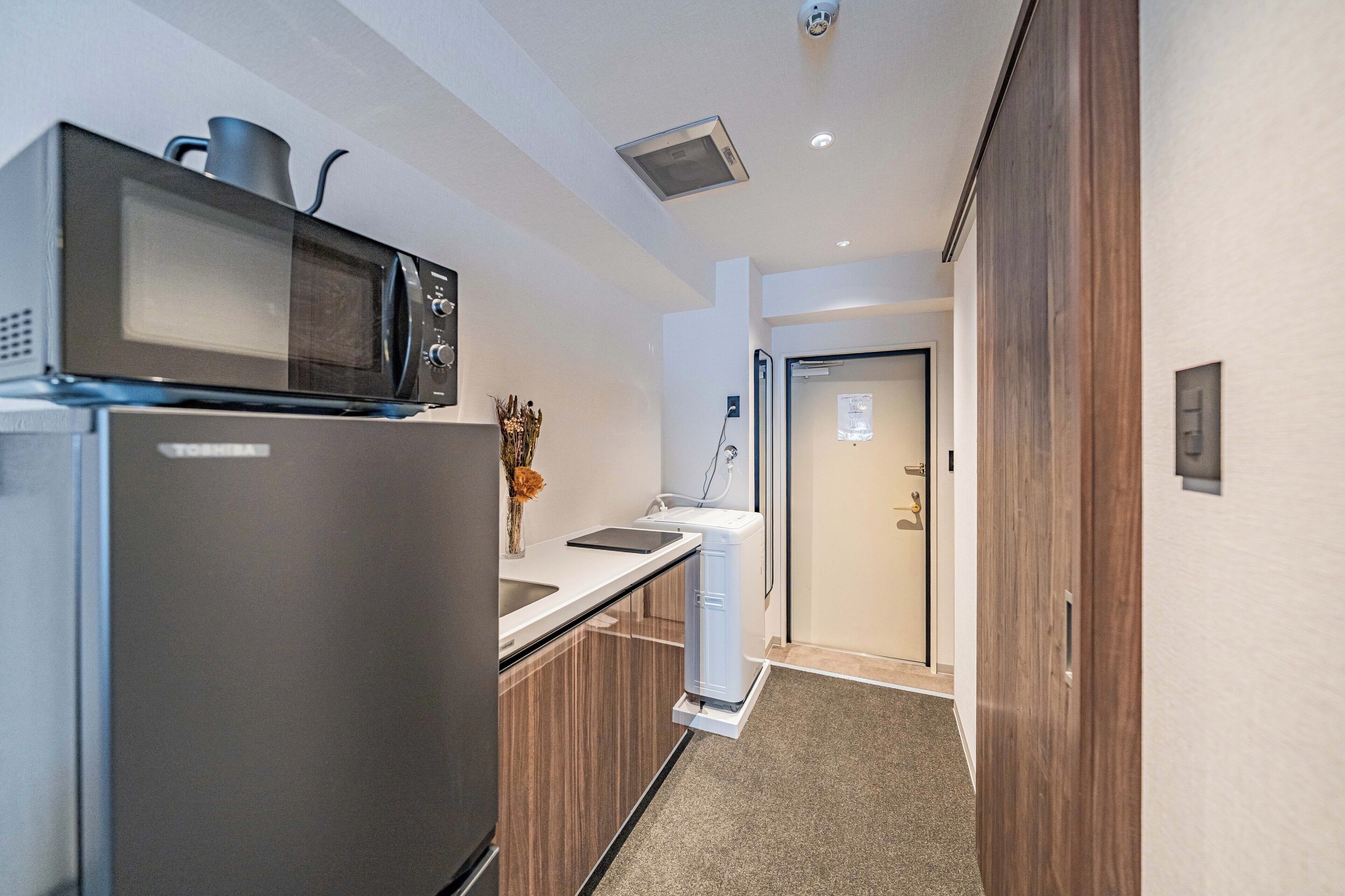 A compact kitchenette with a microwave, refrigerator, and a small sink.