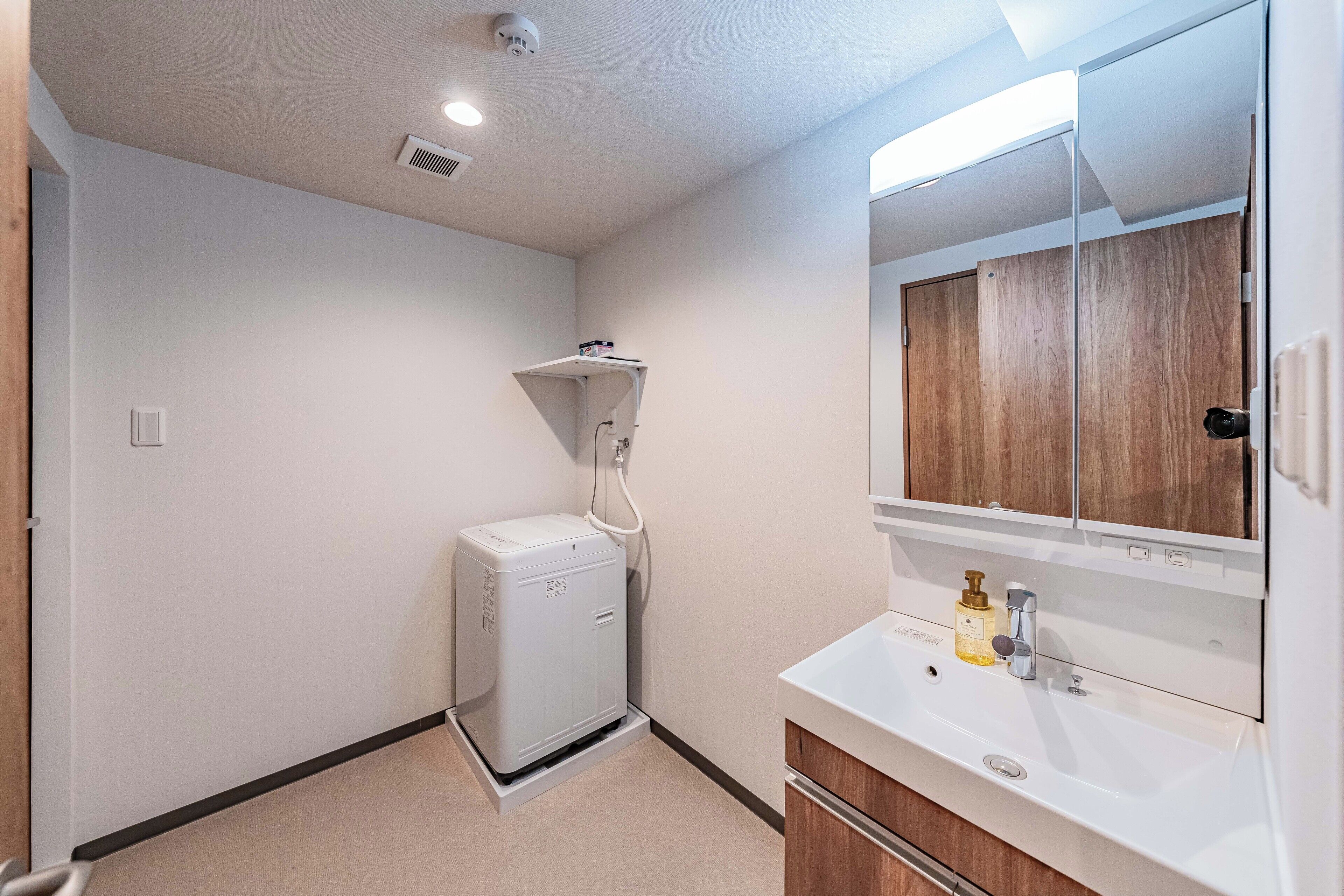 A compact bathroom with a white sink, mirror, and a small heater unit.