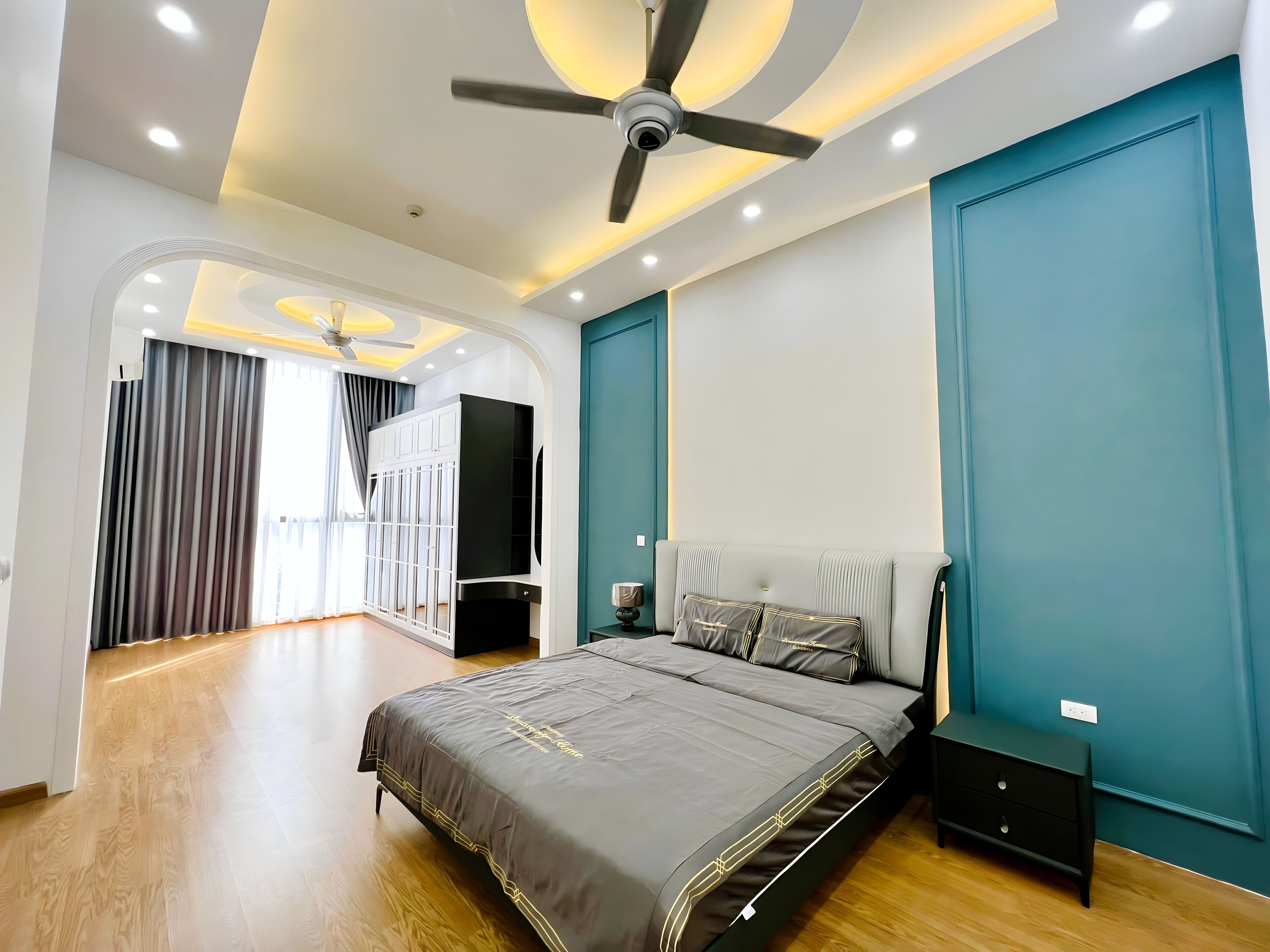 Een moderne slaapkamer met een bed, een kledingkast, een plafondventilator en een nachtkastje.