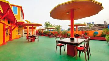 An outdoor dining area with tables and chairs, surrounded by colorful buildings.
