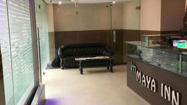 A lobby with a black leather sofa, a reception desk, and a glass display case. - Hotel Maya Inn (Noida)