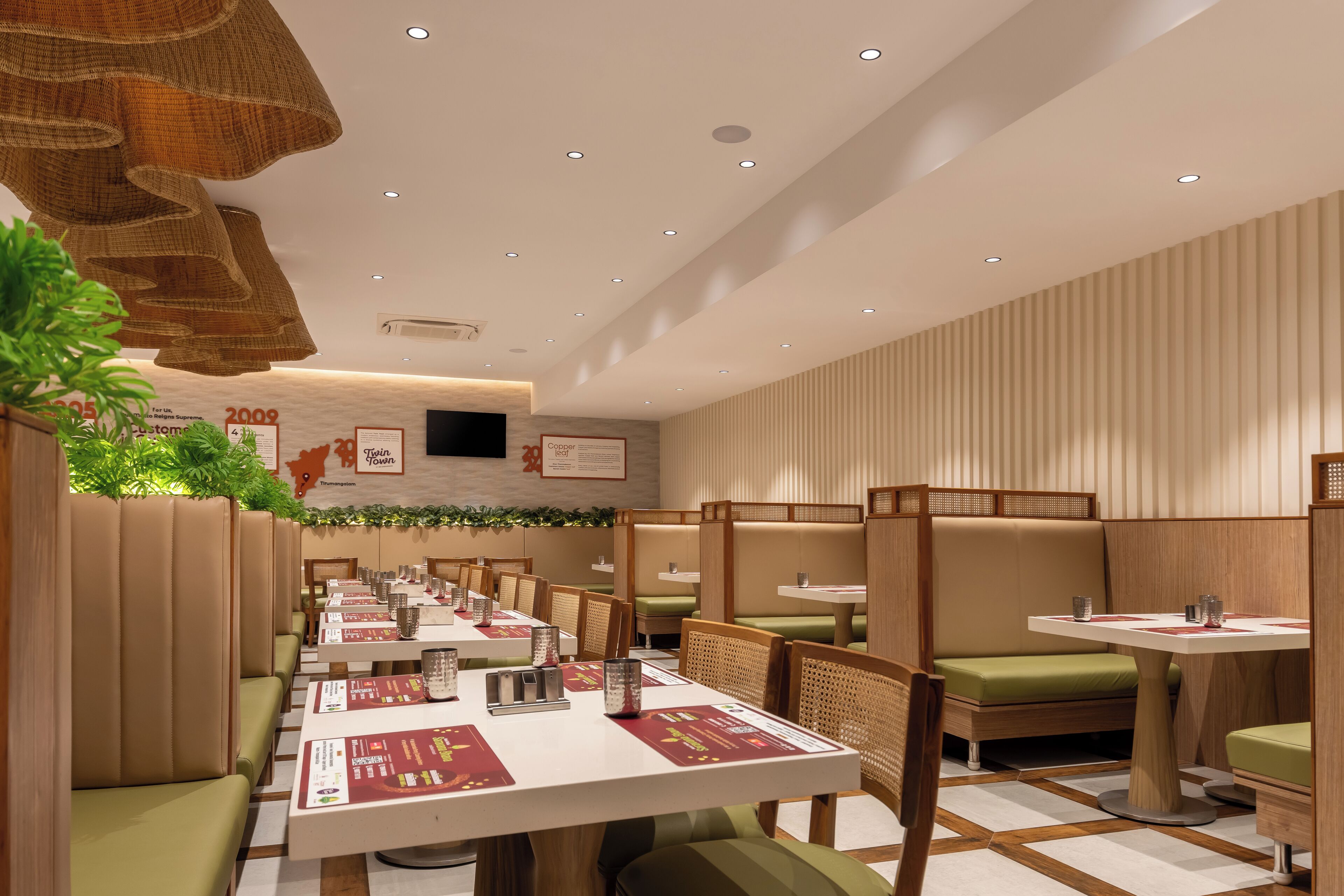 Un restaurante moderno con asientos tipo cabina, mesas de madera y sillas con cojines verdes.