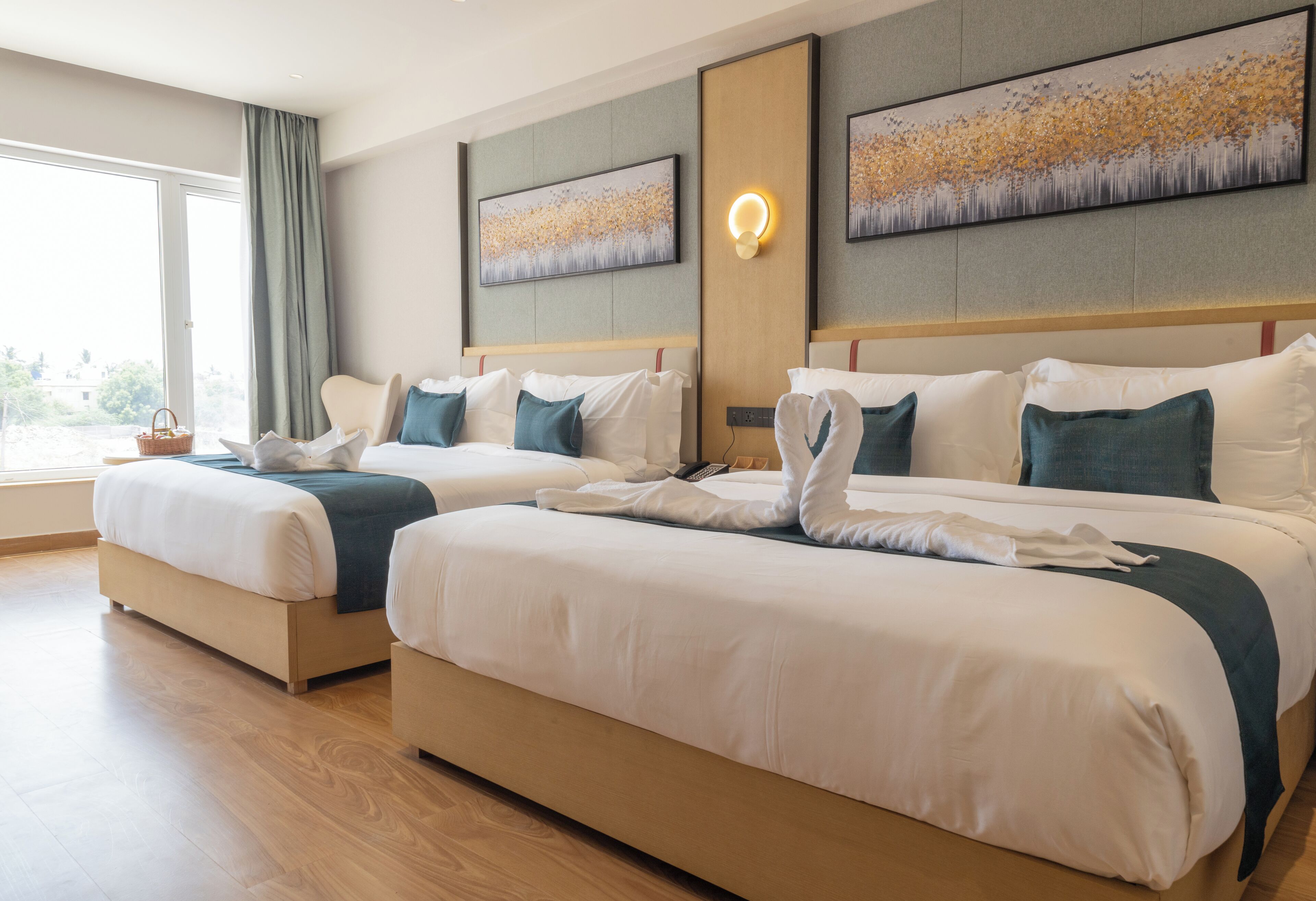 Een hotelkamer met twee bedden, een groot raam en kunstwerken aan de muur.