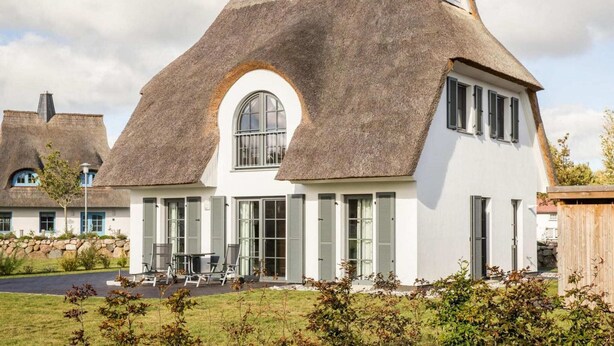 Et moderne hus med stråtækt tag og et stort, buet vindue.