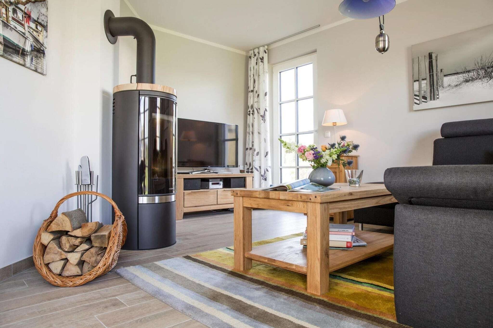 A modern living room with a wood-burning stove, a sofa, a TV, and a dining table.