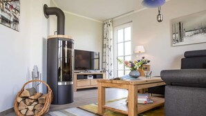 En moderne stue med brændeovn, sofa, fjernsyn og spisebord.