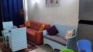 Una sala de estar con un sofá, dos sillones, una mesa de centro y un televisor.