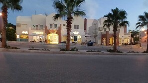 Zona commerciale con un edificio con la scritta 'Better Buns' e palme.