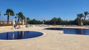 A swimming pool area with lounge chairs and palm trees.