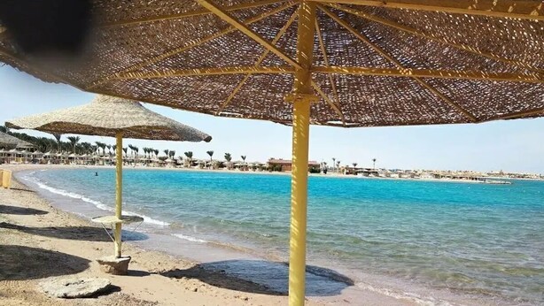A beach with umbrellas and a pool.