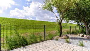 A paved walkway with a metal fence and a tree.