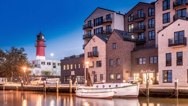 A waterfront building with multiple balconies and a boat docked in front.