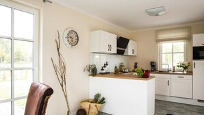 Une cuisine moderne avec des meubles blancs, un îlot central et une grande fenêtre.